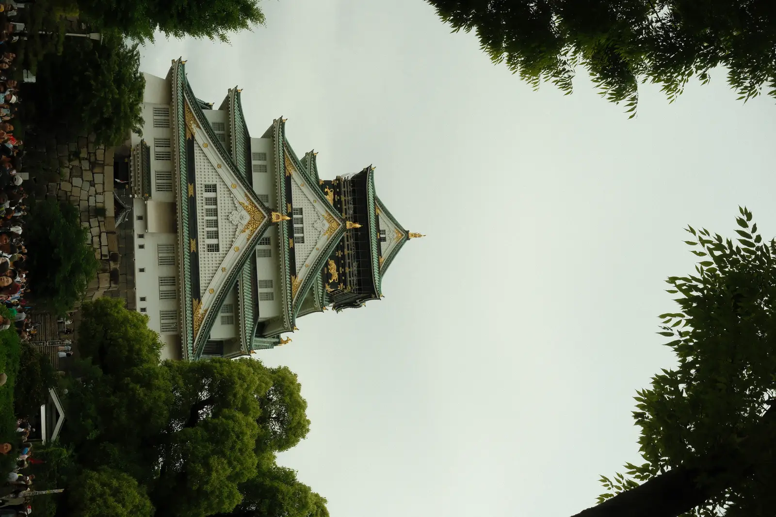 Osaka Castle framed by green trees under a clear sky